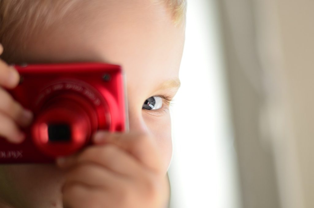 コンデジを右目に構える小さな子供の顔