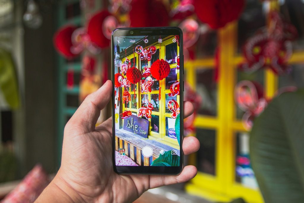 黄色い窓の赤い飾りをスマホで撮影